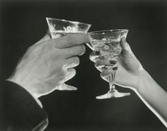 black and white photograph of two people toasting with wine glasses in front of them