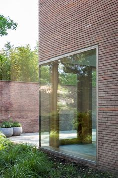 a brick building with large glass windows on the outside and grass in front of it