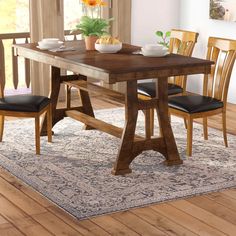 a dining room table with chairs and a rug on the floor