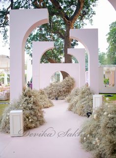 an archway in the middle of a garden with trees and bushes on either side of it