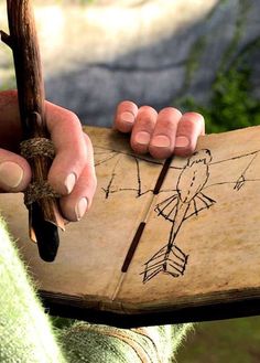 a person holding a piece of wood with a drawing on it