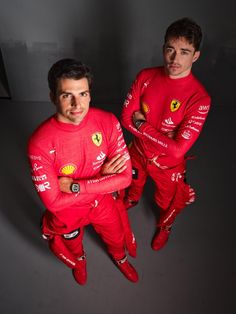 two men in red racing suits are posing for a photo with their hands on their hipss