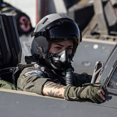 a female fighter pilot sitting in the cockpit of an aircraft looking at her laptop computer