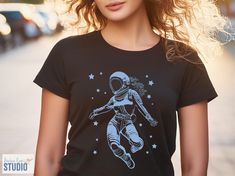 Want a space t-shirt that's out of this world? Our design features a female astronaut grooving to the cosmic beat! This comfy tee is perfect for dancers, space fans, or anyone who dreams of defying gravity. This soft and comfortable shirt lets you celebrate your love for space in style! Shop now and show off your zero-G moves! Available in a range of sizes, grab yours today and show the universe you dance to the beat of your own drum (or spacesuit!).      ♥ FIBER COMPOSITION ♥ Solid colors are 1 Space-themed Cotton T-shirt With Graphic Print, Space-themed Graphic Print Cotton T-shirt, Space-themed Short Sleeve Top With Graphic Print, Space-themed Graphic Print Short Sleeve Tops, Black Cotton Space-themed T-shirt, Black Short Sleeve Space-themed Tops, Black Cotton T-shirt With Space Theme, Space-themed Graphic Crew Neck Tops, Space-themed Short Sleeve T-shirt With Screen Print