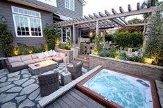 a hot tub sitting on top of a wooden deck next to a patio with furniture