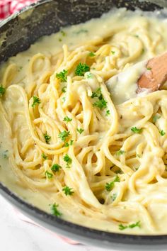 a skillet filled with pasta and parsley on top of a red checkered table cloth