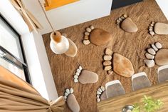 a room with some chairs and rocks on the floor next to a wall that has been made out of sand