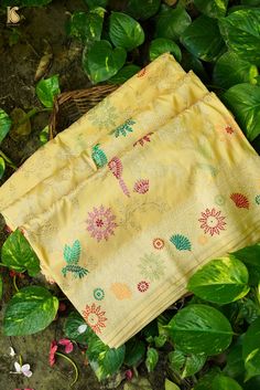 two yellow napkins sitting on top of green leaves