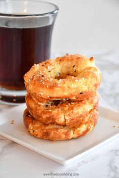 three bagels sitting on top of a white plate next to a cup of coffee