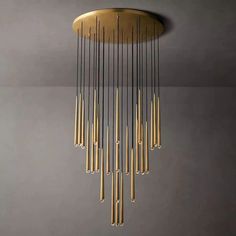 a gold chandelier hanging from the ceiling in a room with grey walls and flooring