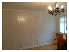 a chandelier hanging from the ceiling in a room with white walls and wood floors