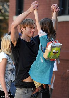 a young man and woman holding hands in the air with other people standing around them