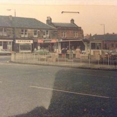 an old photo of people sitting at tables on the side of the road in front of some buildings