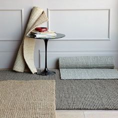 two rugs and a table in a room with white paneling on the wall