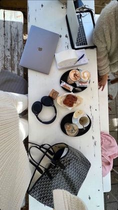 an open laptop computer sitting on top of a white table next to other items and coffee