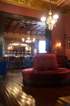 an ornately decorated bar with chandelier and red velvet chair in the foreground