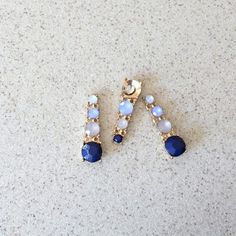 two blue and white earrings sitting on top of a counter