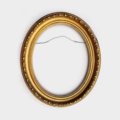 an oval gold frame on a white background with thread in the middle and two holes at the bottom