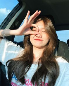 a woman sitting in the back seat of a car holding her hand up to her face