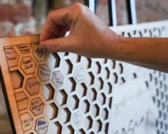 a person's hand holding onto a wooden board with writing on it and hexagonal shapes