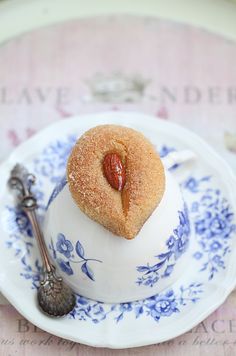 there is a small pastry on top of a teacup with a spoon next to it