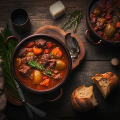 a bowl of stew next to bread and butter on a wooden table with utensils