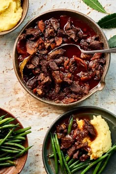 three plates with green beans, mashed potatoes and beef in sauce on the table