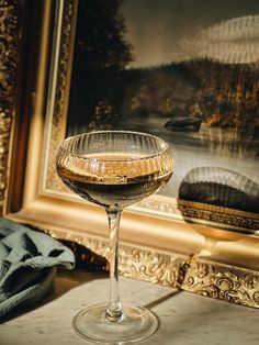 a glass of wine sitting on top of a table next to a painting and towel