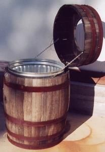 a wooden barrel sitting on top of a table next to a metal container filled with water