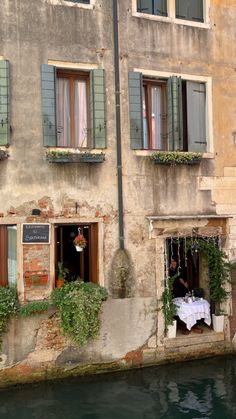 an old building that has some windows on the side and people sitting at a table in front of it