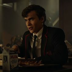 a man in a suit and tie sitting at a table with some food on it