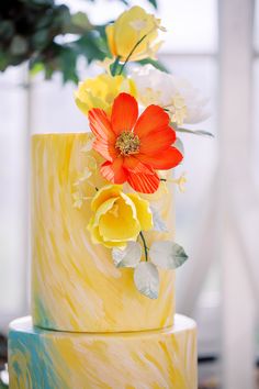 a yellow and blue cake with flowers on top