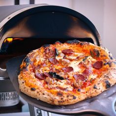 a pizza sitting on top of an oven with pepperoni and olives in it