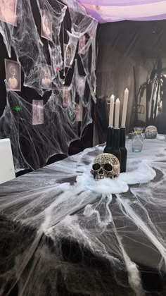 a table topped with candles and a skull covered in spiderwetches on top of it