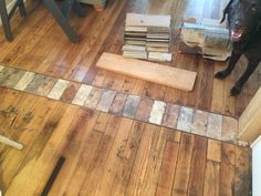 a black dog standing on top of a wooden floor next to a pile of wood