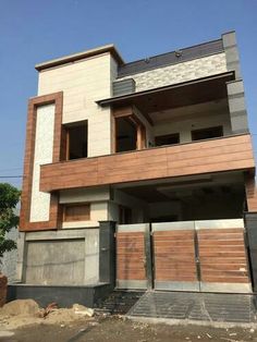 a two story house with wooden garage doors on the front and side of it, surrounded by trees