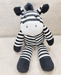 a zebra stuffed animal sitting on top of a white couch with black and white stripes