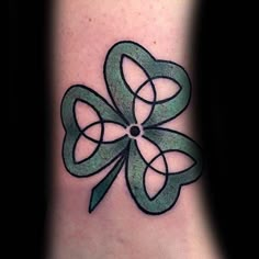 a shamrock tattoo on the ankle with four leaf clovers in green and black ink