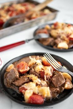 two black plates with food on them and a fork in the plate next to it