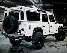 a white jeep parked in a garage with large tires on it's front wheels