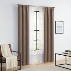 a living room filled with furniture and a window covered in brown drapes, next to a white rug