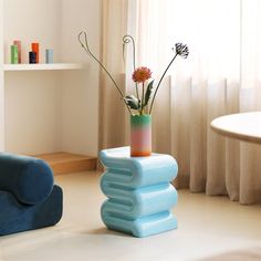 there is a vase with flowers in it sitting on three blue stools next to a window