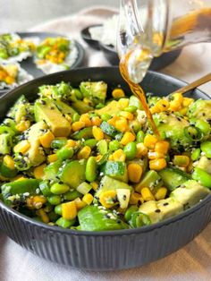 a pan filled with vegetables and dressing being poured into it