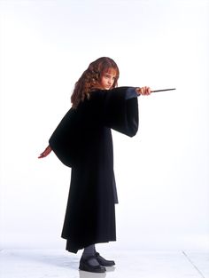 a woman in black holding a wand and pointing it at the camera with her right hand