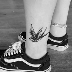 a small bird tattoo on the leg of a woman's lower body and foot