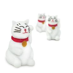 three small white cat figurines sitting next to each other