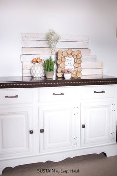 two vases with flowers are sitting on top of a white buffet side cabinet in the kitchen