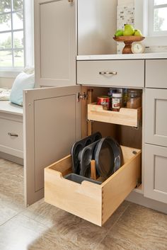 an open drawer in the middle of a kitchen with black pots and pans inside