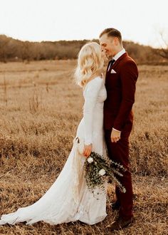 a bride and groom are standing in the middle of an open field with their arms around each other