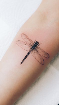 a small dragonfly tattoo on the arm